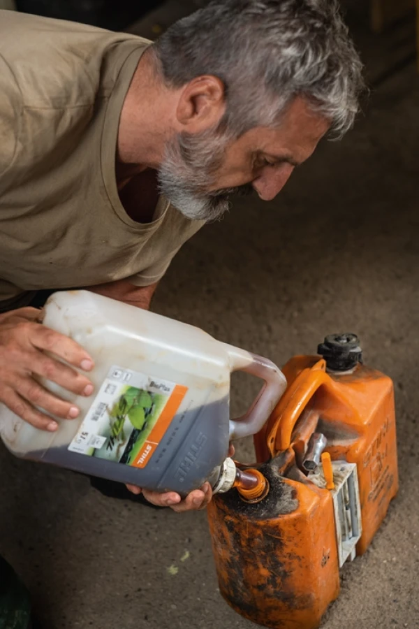 Un homme versant du carburant dans un bidon