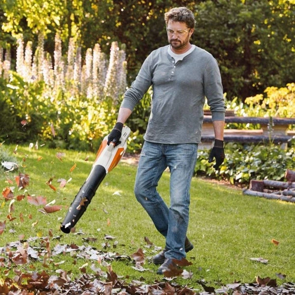 Un homme qui souffle les feuilles dans son jardin